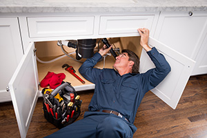 contractor laying under sink for plumbing repair